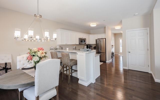 kitchen featuring a notable chandelier, dark wood-type flooring, stainless steel appliances, white cabinetry, and kitchen peninsula