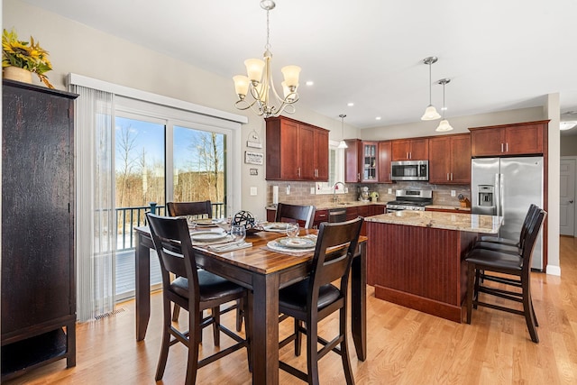 dining area with sink, an inviting chandelier, and light hardwood / wood-style floors