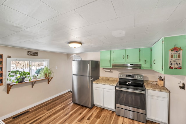 kitchen featuring light wood-type flooring, stainless steel appliances, white cabinetry, and light stone counters