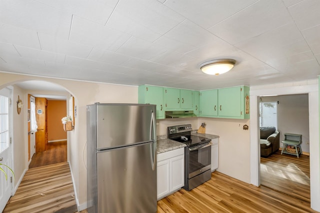 kitchen featuring light wood-type flooring, appliances with stainless steel finishes, light stone countertops, and green cabinetry