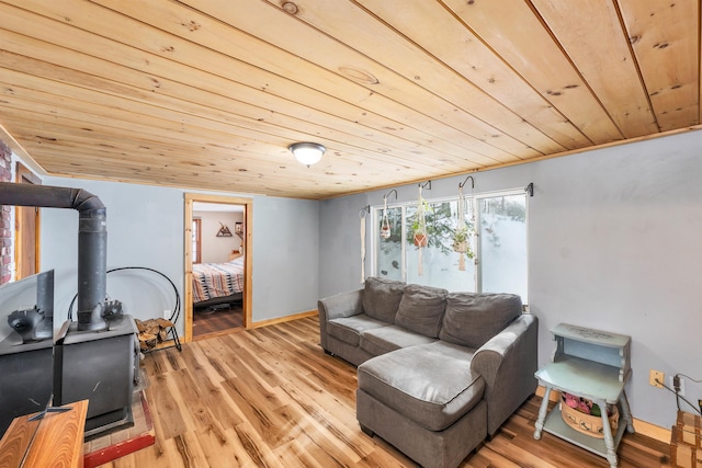 living room featuring light wood-type flooring, a wood stove, and wooden ceiling