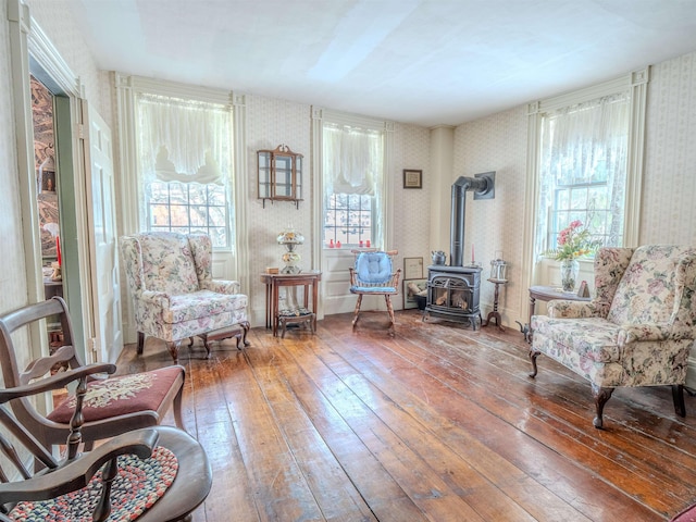 sitting room featuring a wood stove and wood-type flooring