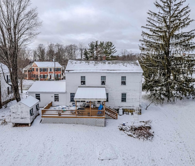 snow covered back of property with a wooden deck