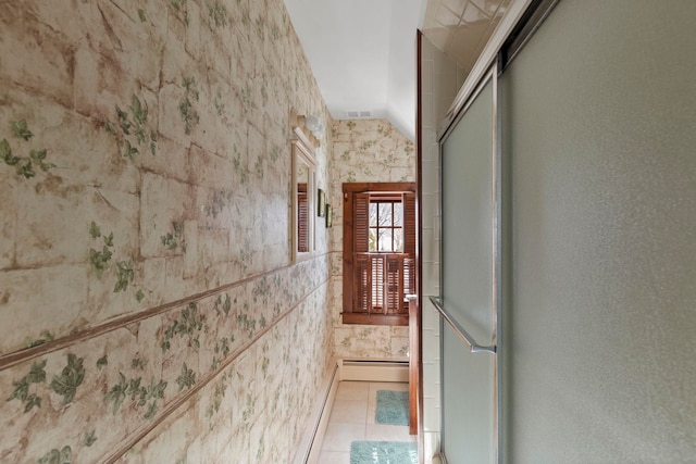 corridor with a baseboard heating unit and light tile patterned floors