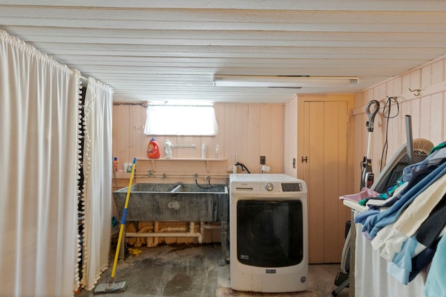 clothes washing area featuring sink, washer / dryer, and wood walls