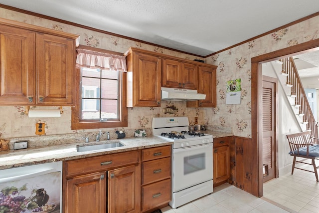 kitchen featuring light stone counters, a textured ceiling, white gas stove, ornamental molding, and sink