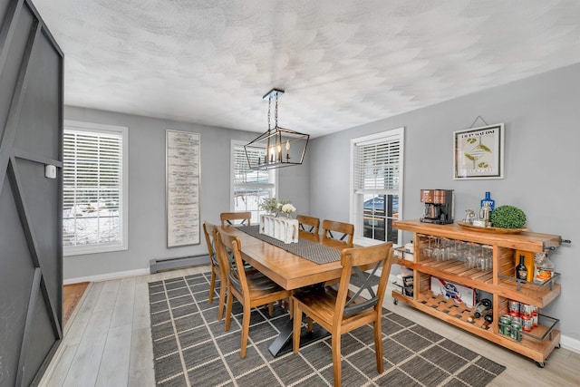 dining room with a textured ceiling, hardwood / wood-style floors, an inviting chandelier, and baseboard heating