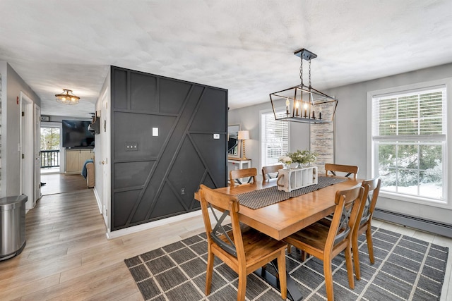 dining area with light wood-type flooring and baseboard heating