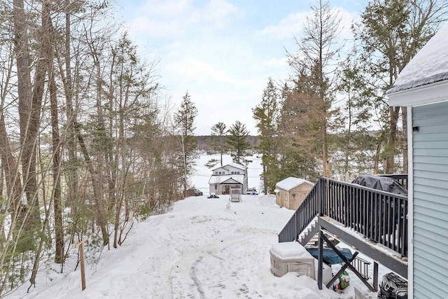 yard layered in snow featuring a storage unit and a deck