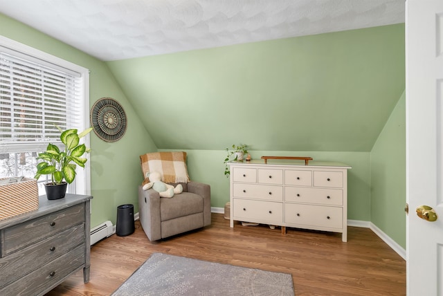 living area with light hardwood / wood-style flooring, a baseboard heating unit, and lofted ceiling