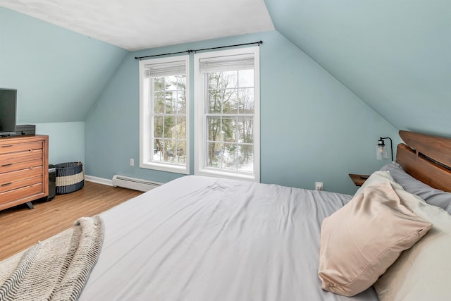 bedroom with light hardwood / wood-style floors, vaulted ceiling, and a baseboard heating unit