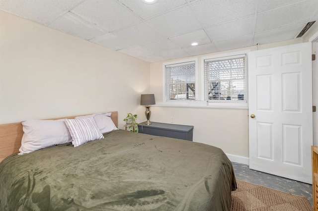 bedroom featuring concrete flooring and a paneled ceiling