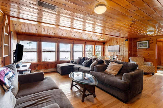 living room with light wood finished floors, wood ceiling, wooden walls, and visible vents