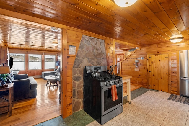 kitchen featuring stainless steel appliances, wood walls, light tile patterned flooring, and wood ceiling