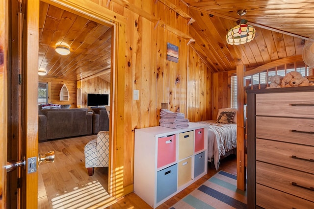 bedroom with lofted ceiling, wooden ceiling, wooden walls, and wood finished floors