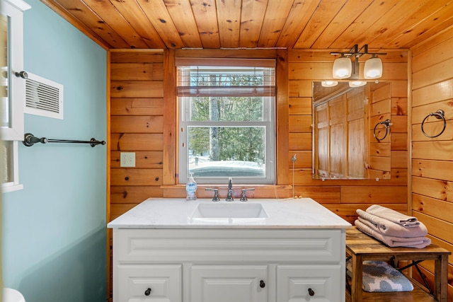 bathroom featuring wooden ceiling, vanity, and wooden walls