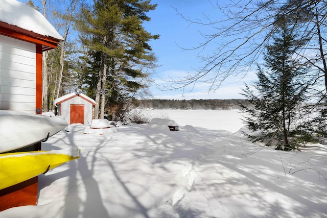 yard layered in snow featuring a storage unit and an outbuilding