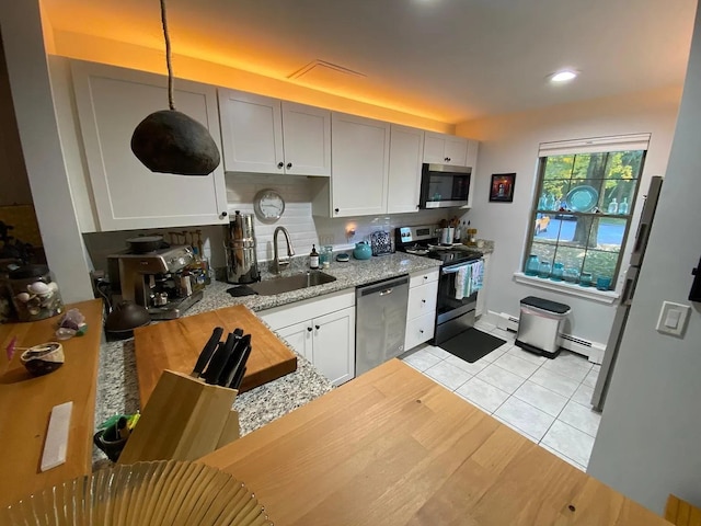 kitchen featuring stainless steel appliances, light stone countertops, white cabinets, pendant lighting, and sink