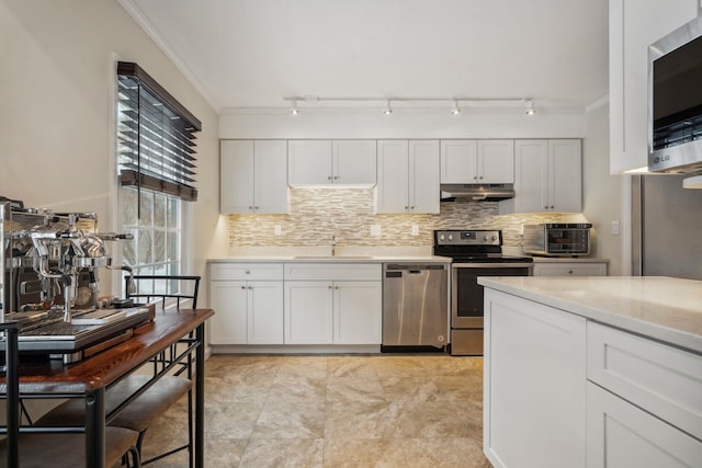 kitchen with appliances with stainless steel finishes, light stone counters, crown molding, white cabinets, and decorative backsplash