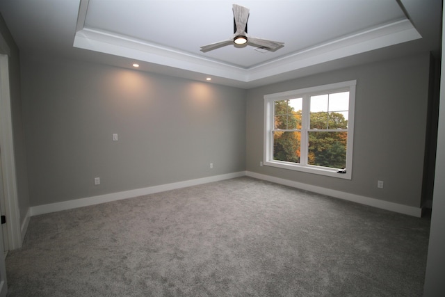 carpeted spare room with a tray ceiling and ceiling fan