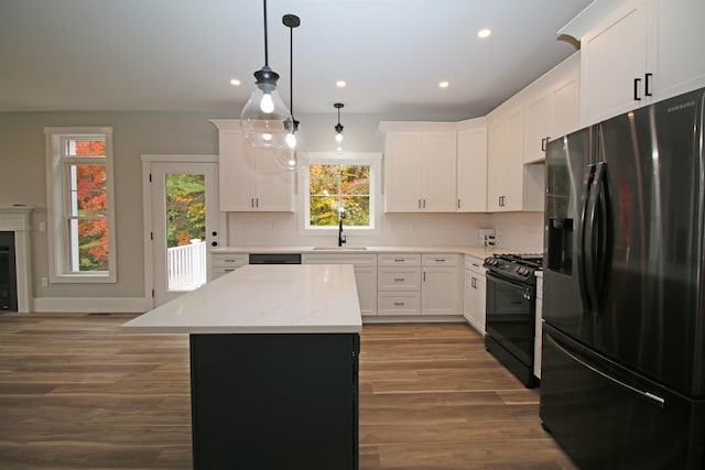 kitchen featuring stainless steel refrigerator with ice dispenser, a kitchen island, sink, white cabinetry, and black gas range oven