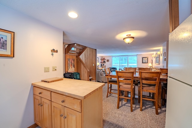 kitchen with light brown cabinetry, butcher block countertops, a textured ceiling, white refrigerator, and light colored carpet