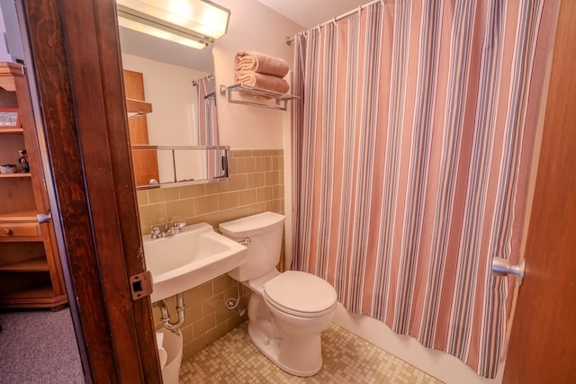 full bathroom with toilet, shower / bath combo with shower curtain, tile walls, tile patterned floors, and sink