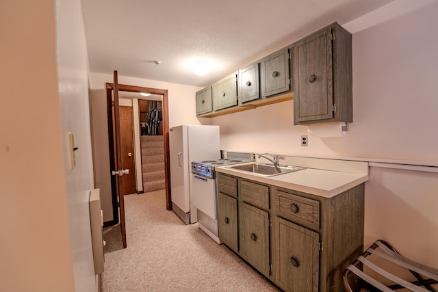 kitchen featuring sink, white appliances, a textured ceiling, and light colored carpet