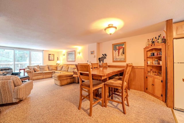 dining area featuring a textured ceiling and light colored carpet