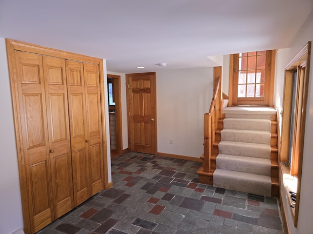 foyer featuring stairs and baseboards