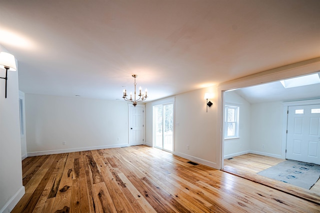 interior space featuring vaulted ceiling, a notable chandelier, and light hardwood / wood-style flooring