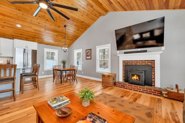 living room featuring high vaulted ceiling, light hardwood / wood-style floors, wood ceiling, ceiling fan, and a fireplace