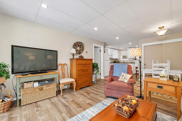 living room with light hardwood / wood-style floors and a paneled ceiling