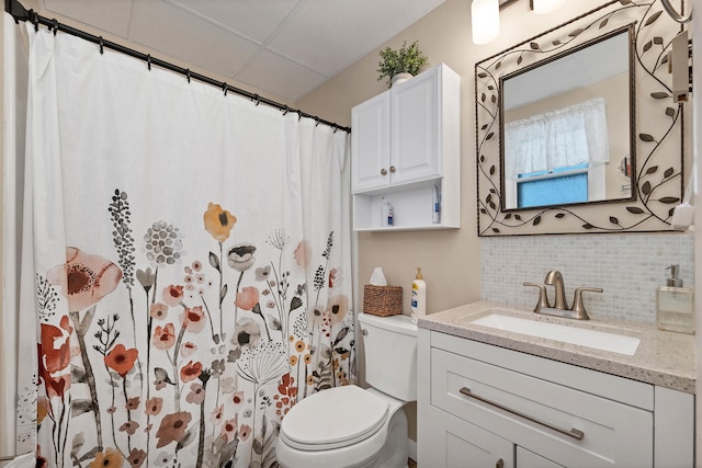 bathroom featuring vanity, a paneled ceiling, toilet, and backsplash