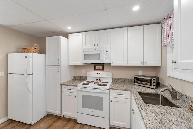 kitchen with light wood-type flooring, sink, white appliances, a paneled ceiling, and white cabinets