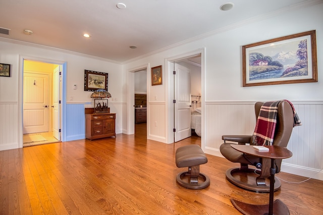 living area with hardwood / wood-style flooring and crown molding