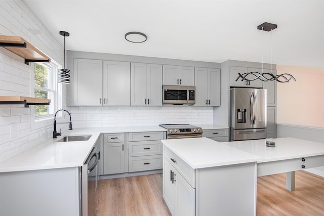 kitchen featuring a center island, appliances with stainless steel finishes, sink, and decorative light fixtures