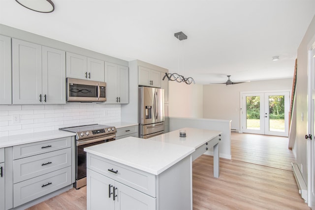 kitchen with stainless steel appliances, decorative light fixtures, a kitchen island, gray cabinets, and decorative backsplash