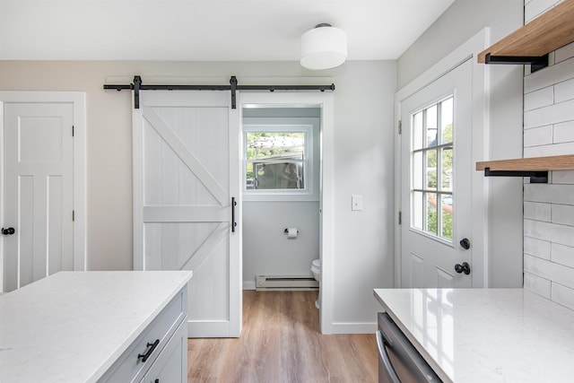 interior space with light hardwood / wood-style flooring, a barn door, dishwashing machine, light stone countertops, and a baseboard heating unit