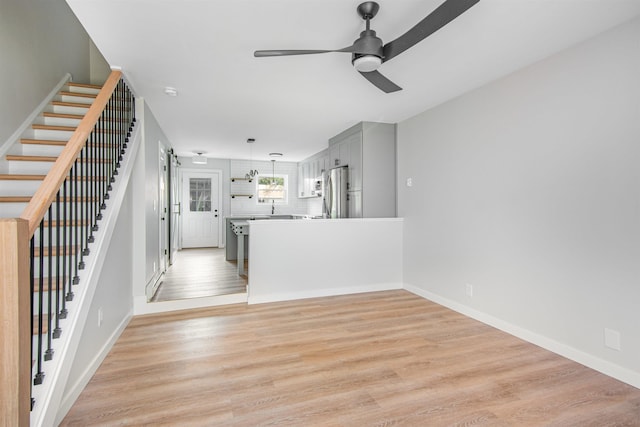 unfurnished living room with light wood-type flooring and ceiling fan