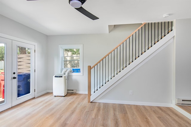 interior space with light wood-type flooring, french doors, ceiling fan, and a baseboard heating unit