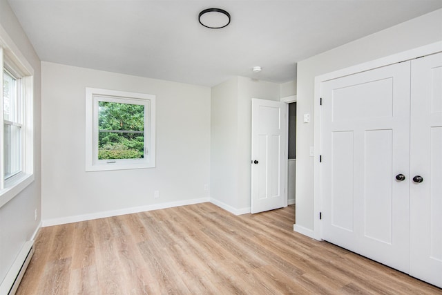 unfurnished bedroom with light hardwood / wood-style floors, baseboard heating, and a closet