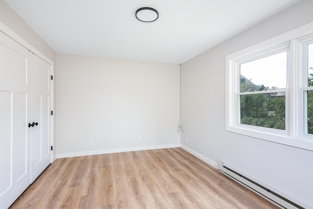 empty room with light hardwood / wood-style floors and a baseboard heating unit