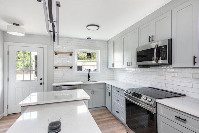 kitchen with appliances with stainless steel finishes, plenty of natural light, hanging light fixtures, gray cabinetry, and sink