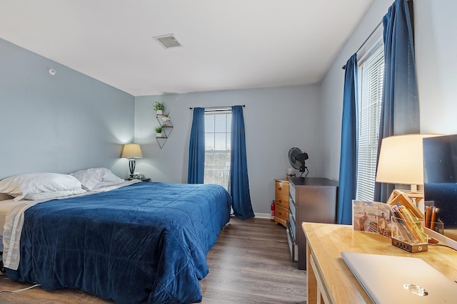 bedroom with multiple windows and dark hardwood / wood-style floors