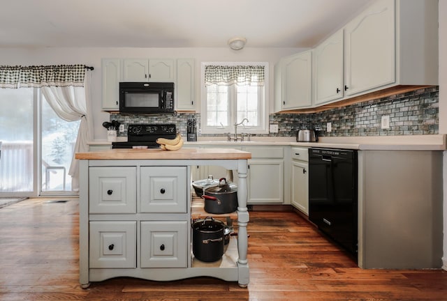 kitchen with tasteful backsplash, black appliances, white cabinets, and dark hardwood / wood-style floors