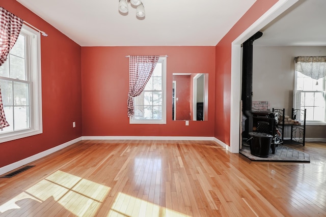 empty room with light wood-type flooring and a wood stove