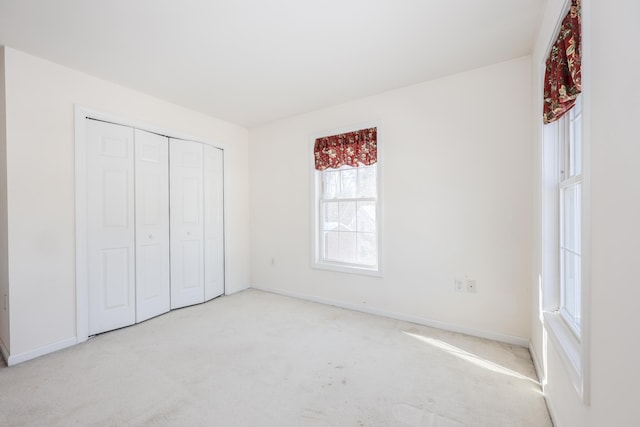 unfurnished bedroom featuring light carpet and a closet