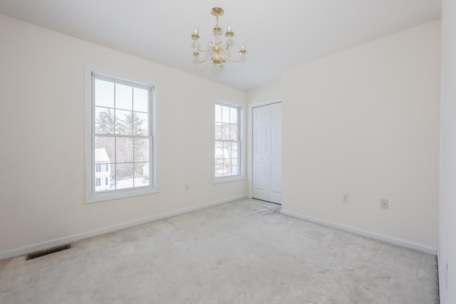 unfurnished room with an inviting chandelier and light colored carpet