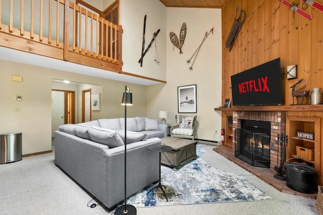 living room with a fireplace, a high ceiling, light colored carpet, and wooden walls